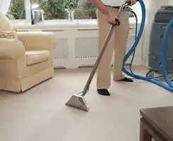 Carpet cleaning professional removing dirt and stains with a hot-water extraction tool in a home, Aurora, CO.