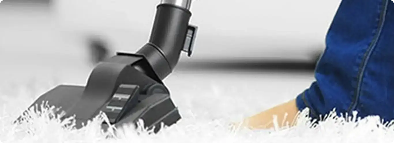 Close-up of a professional vacuuming a white carpet in Watkins.