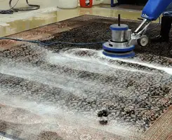 Professional rug cleaning with a rotary floor machine and shampoo foam, deep-cleaning an area rug, in Aurora, CO.